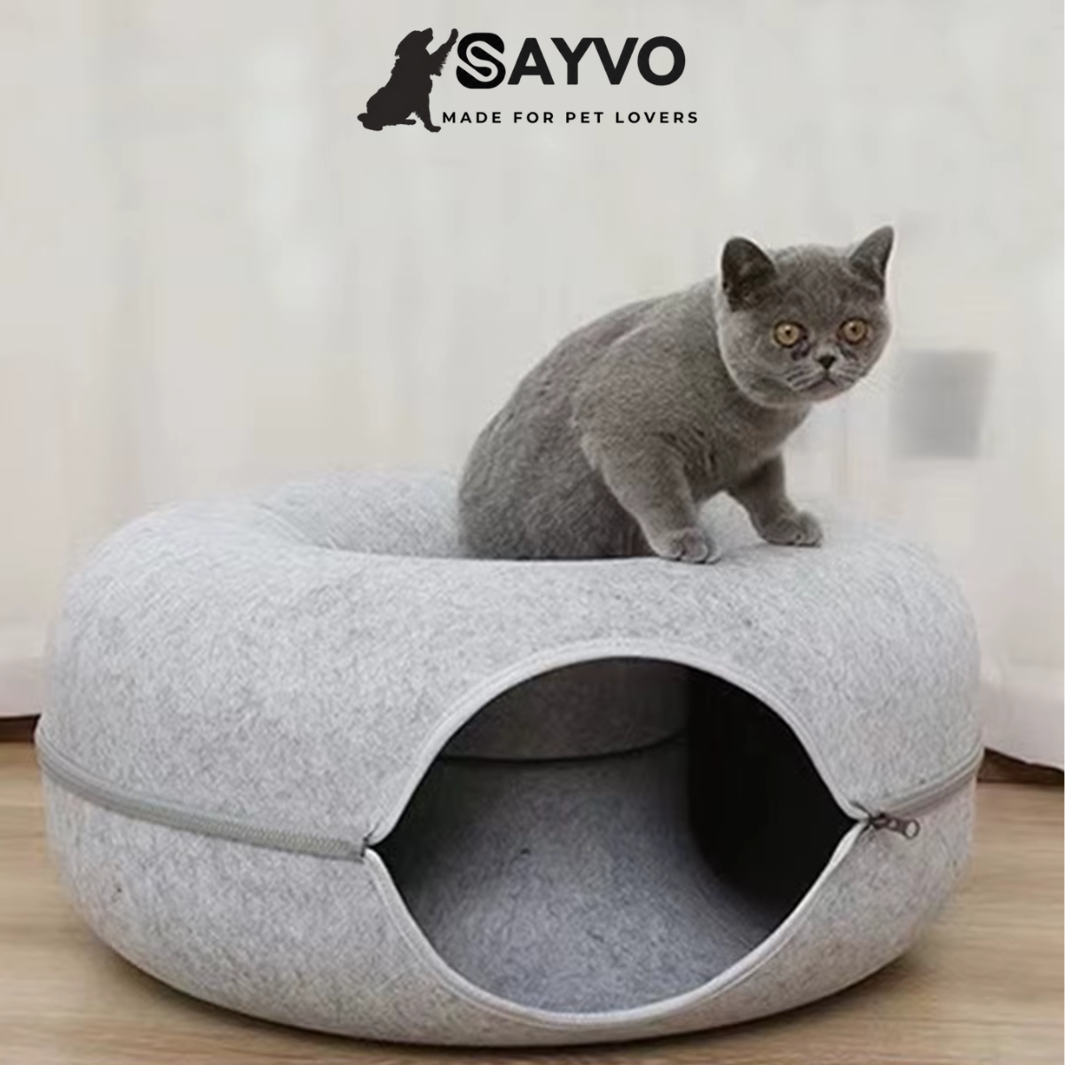 Grey cat sitting on a light grey donut-shaped cat tunnel bed with an enclosed circular tunnel and zippered detachable design.